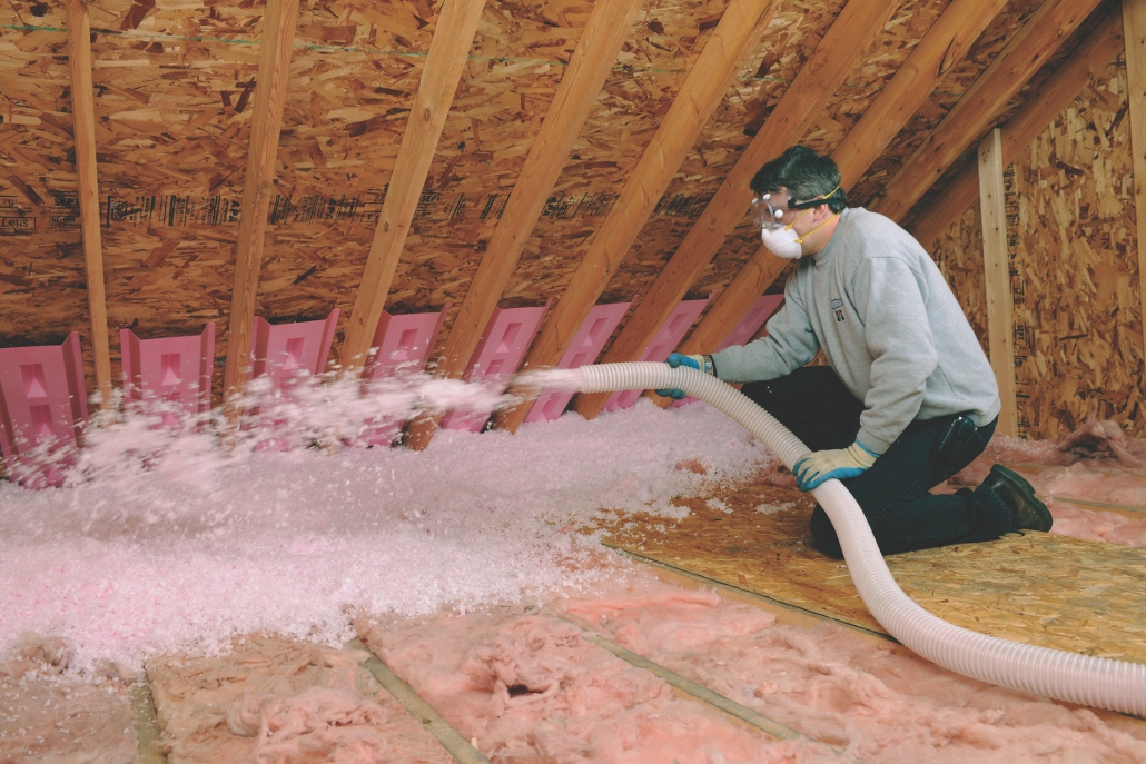 Installer blowing loose-fill insulation across an attic floor